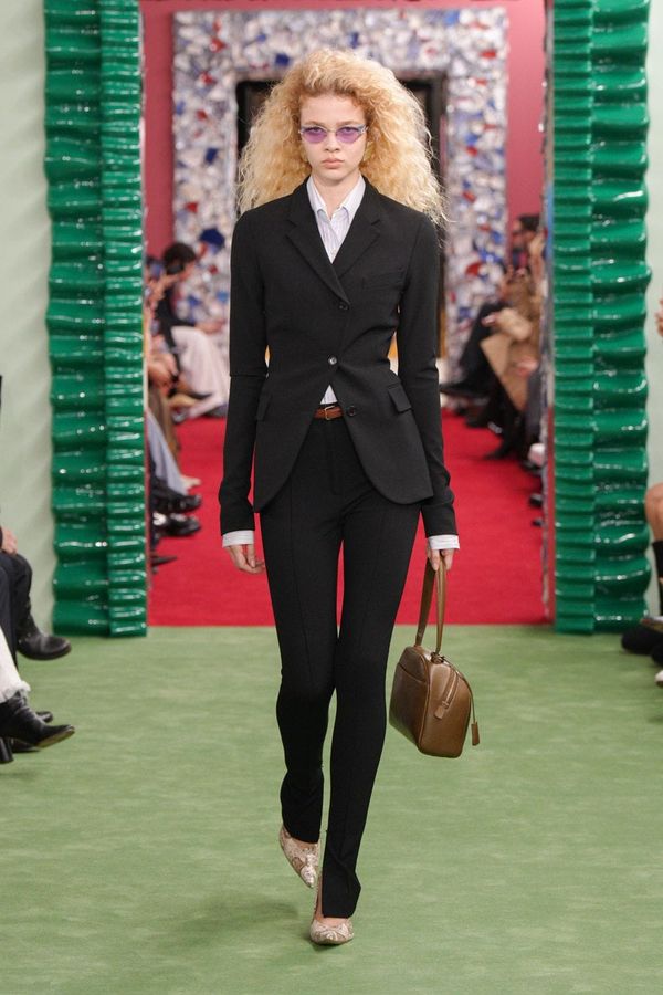 A runway shot from Acne Studios Fall 2026 showing one of the collection's architectural tailored pieces—ideally an oversized blazer or structured trouser look in the charcoal or camel pale...