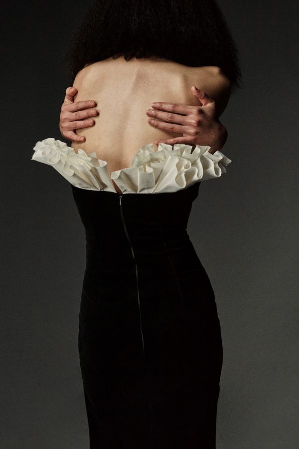 A runway shot from A.W.A.K.E. Mode Fall 2026 showing one of the sculptural coats or architecturally precise silhouettes — ideally the opening look with the sharp shoulders and structured w...