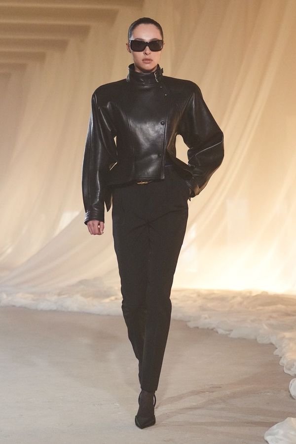 A runway image from Balmain Fall 2026 showing a signature look—ideally a structured jacket with military detailing or heavy embellishment, sharp shoulders, and the kind of high-octane glam...