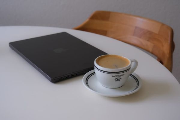 Laptop and coffee cup on a white table