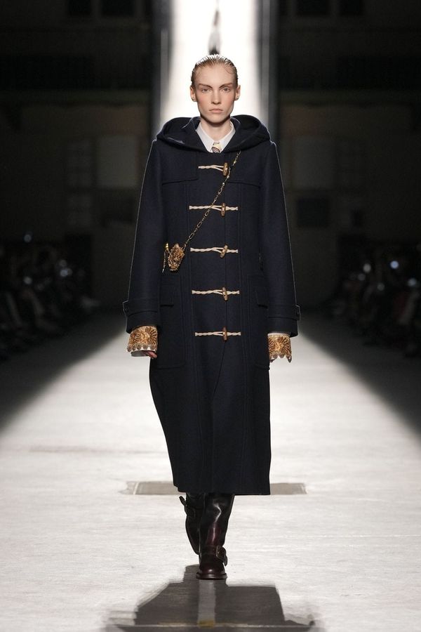 A runway look from the Dries Van Noten Fall 2026 collection—ideally showing the house's signature layered prints and rich textile work. The image should capture both the continuity of the ...