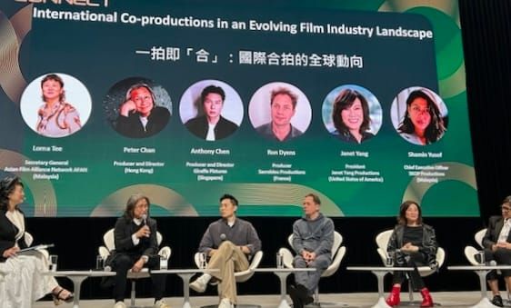 Wide shot of the Filmart panel with Peter Chan, Anthony Chen, and Janet Yang on stage — industry conference setting, serious discussion atmosphere