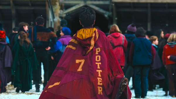 The first official image from HBO's Harry Potter series showing Dominic McLaughlin as Harry Potter in his Gryffindor cloak walking toward the Quidditch pitch