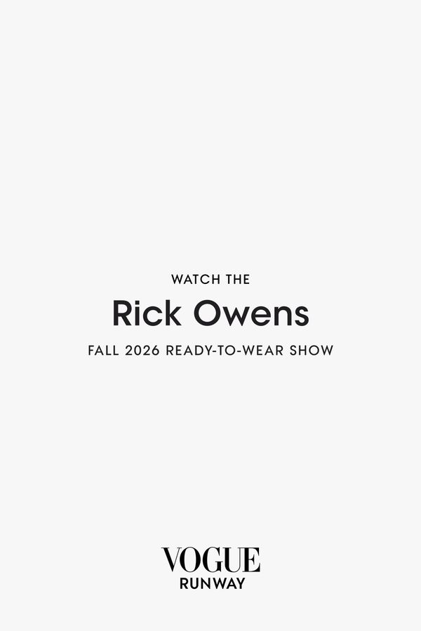 A full-length runway shot from Rick Owens Fall 2026 showing a model in one of the collection's signature draped silhouettes with exaggerated proportions—ideally featuring the platform boot...