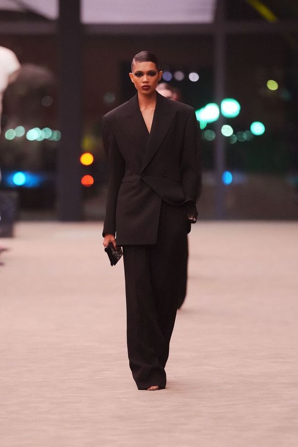 A runway shot from the Saint Laurent Fall 2026 show—ideally a look that captures the house's signature tailoring and rock-and-roll aesthetic. Sharp shoulders, leather, moody lighting. The ...