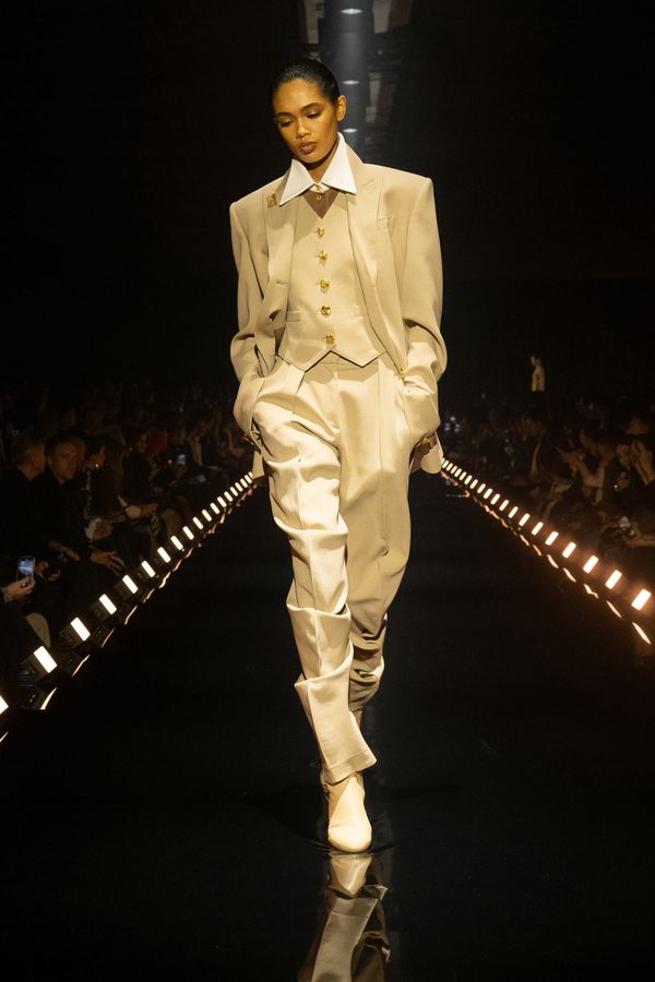 A runway shot from Schiaparelli Fall 2026 showing the anatomical embroidery detail on tailoring—close enough to see the precision of the nervous system mapping, but wide enough to capture ...