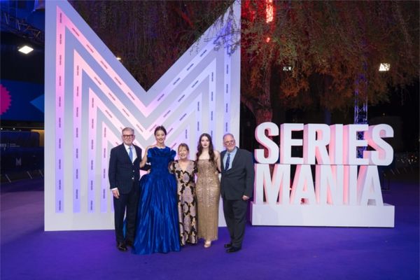 A still from The Testaments showing the privileged women of Gilead — Wives or Aunts in their formal attire, positioned in Gilead's institutional spaces rather than domestic suffering