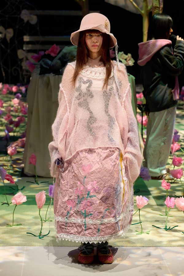 A runway look from Yushokobayashi Fall 2026 showing the architectural tailoring and layering — ideally a full-length shot of a structured coat over asymmetric pleated trousers in the neutr...