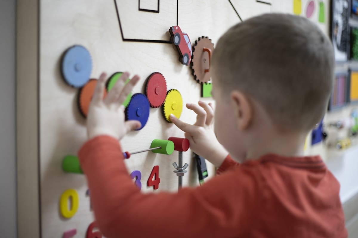 Young boy playing with shapes on a wall-mounted board