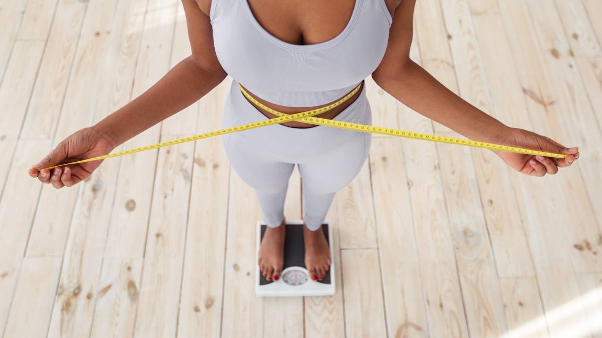 Woman standing on scales measuring her waist.