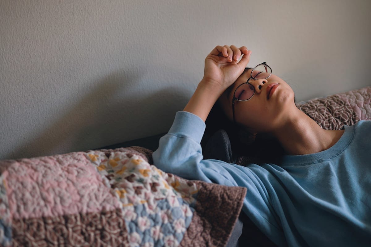Young Asian woman in glasses looking distressed on her couch