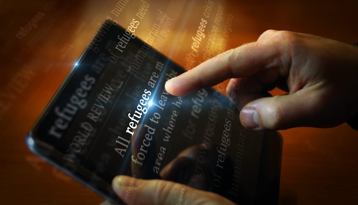 News titles on screen in hand with Refugee