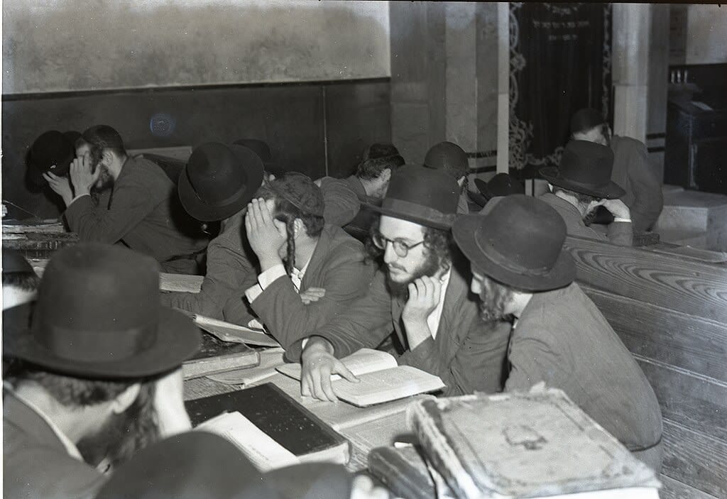 A group of seated ultra-Orthodox Jewish men with books in 1950