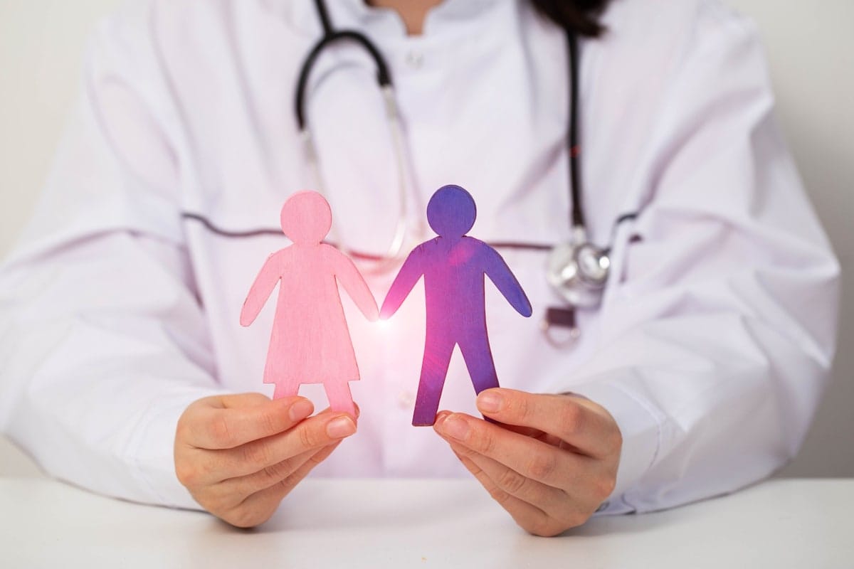 Doctor holds figurines of a female and a male.