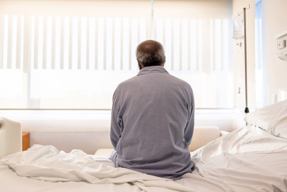 Depressed man man sitting on a hospital bed with his back to the camera