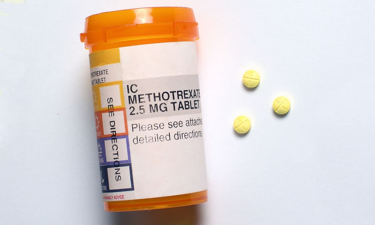 A pill bottle labelled methotrexate with scattered pills