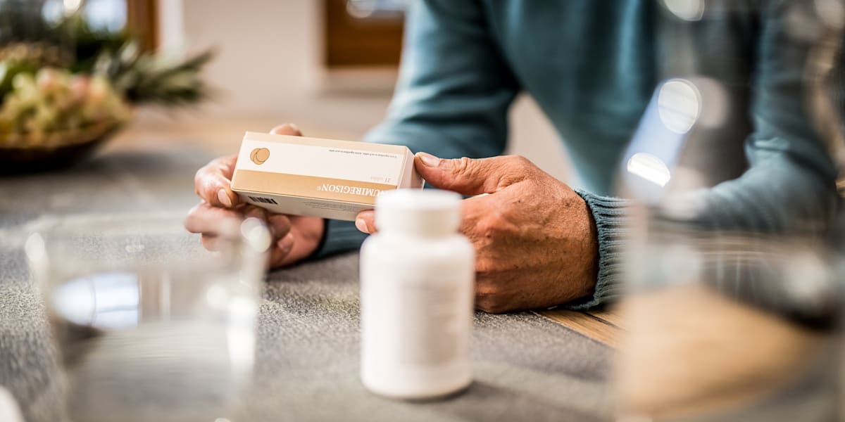 Male hands holding medicine box and reading instruction