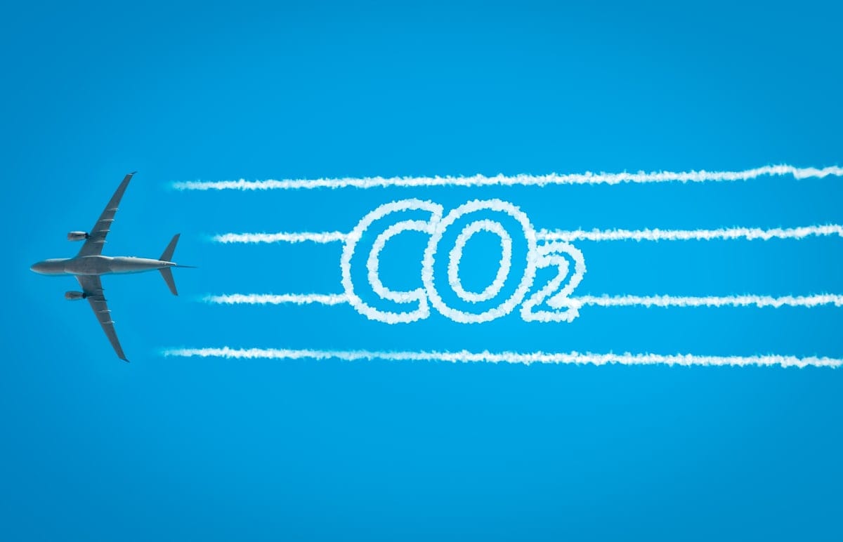 Airplane leaving jet contrails with CO2 word inside. 