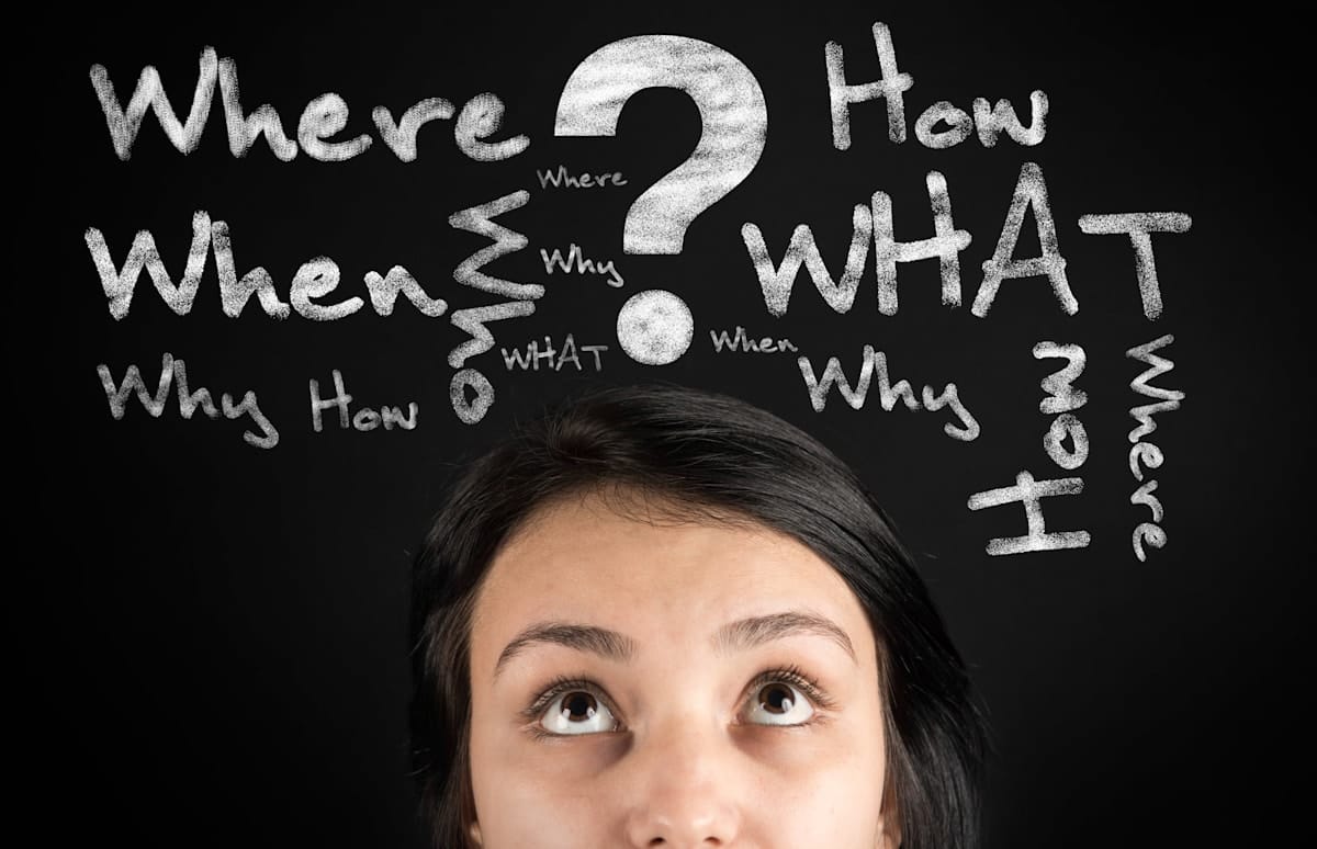 Questions on a black board above a young woman