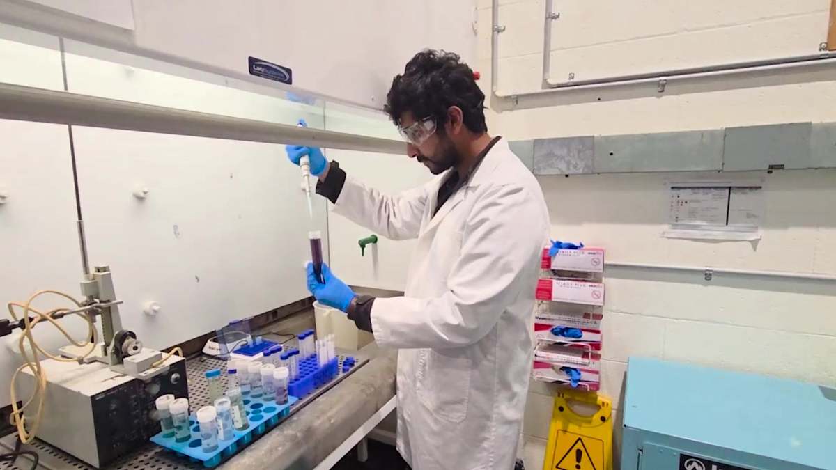 Scientist in a lab coat working with a pipette and test tubes