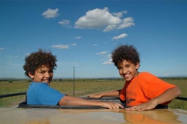 Jomo and Jamali Kigotho in Kenya, aged 10 and nine, looking back towards the camera and smiling