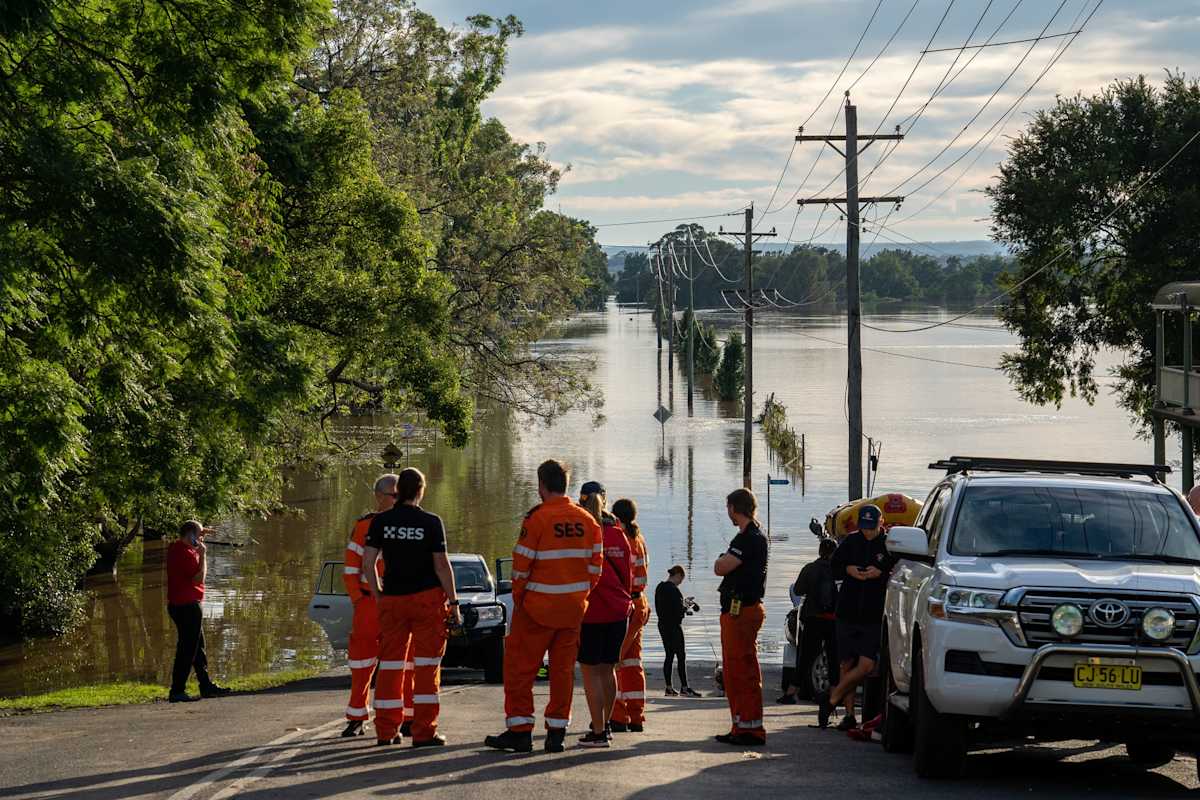 Emergency services workers stand on a flooded road in  Western Sydney Floods.