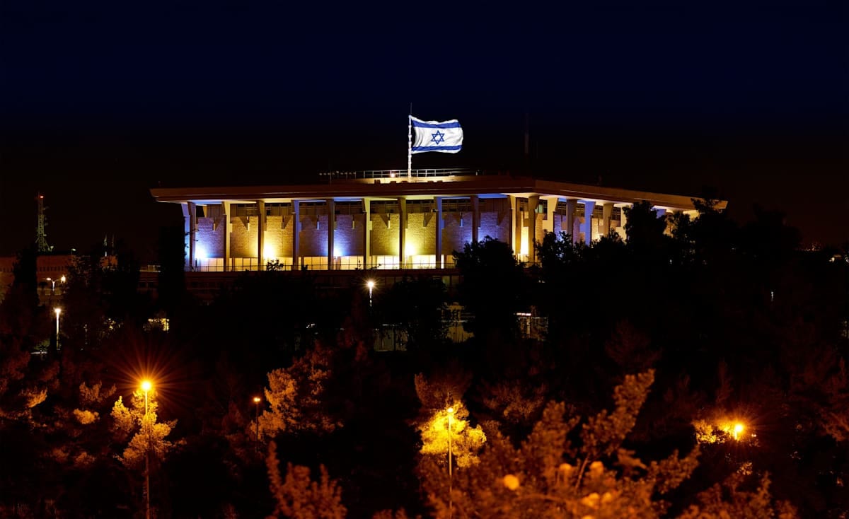 The Knesset at night  with Israel flag flying.