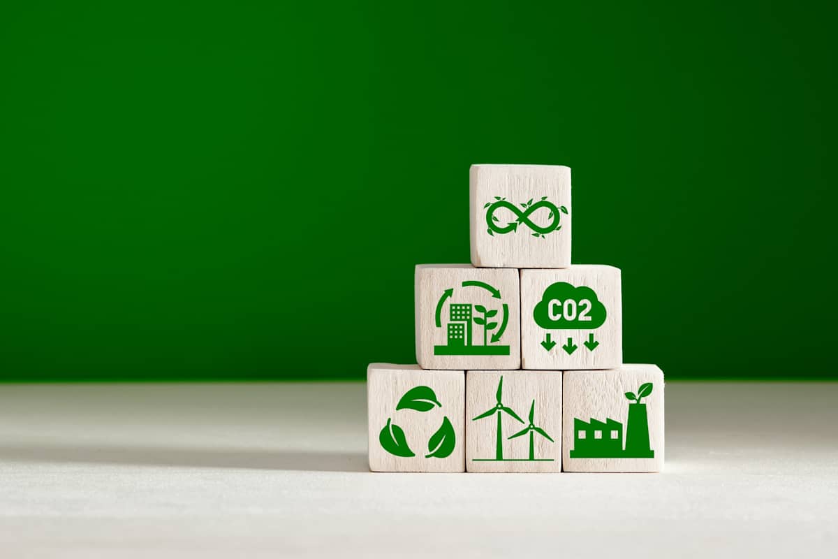 climate change concept. Business and environment sustainable development. Stacked wooden cubes with eco infinity and environment sustainable symbols on green background.