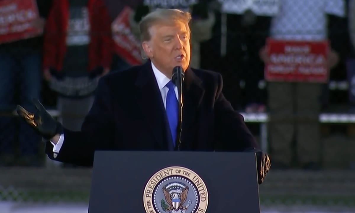 Donal Trump, wearing gloves, addressing a campaign rally