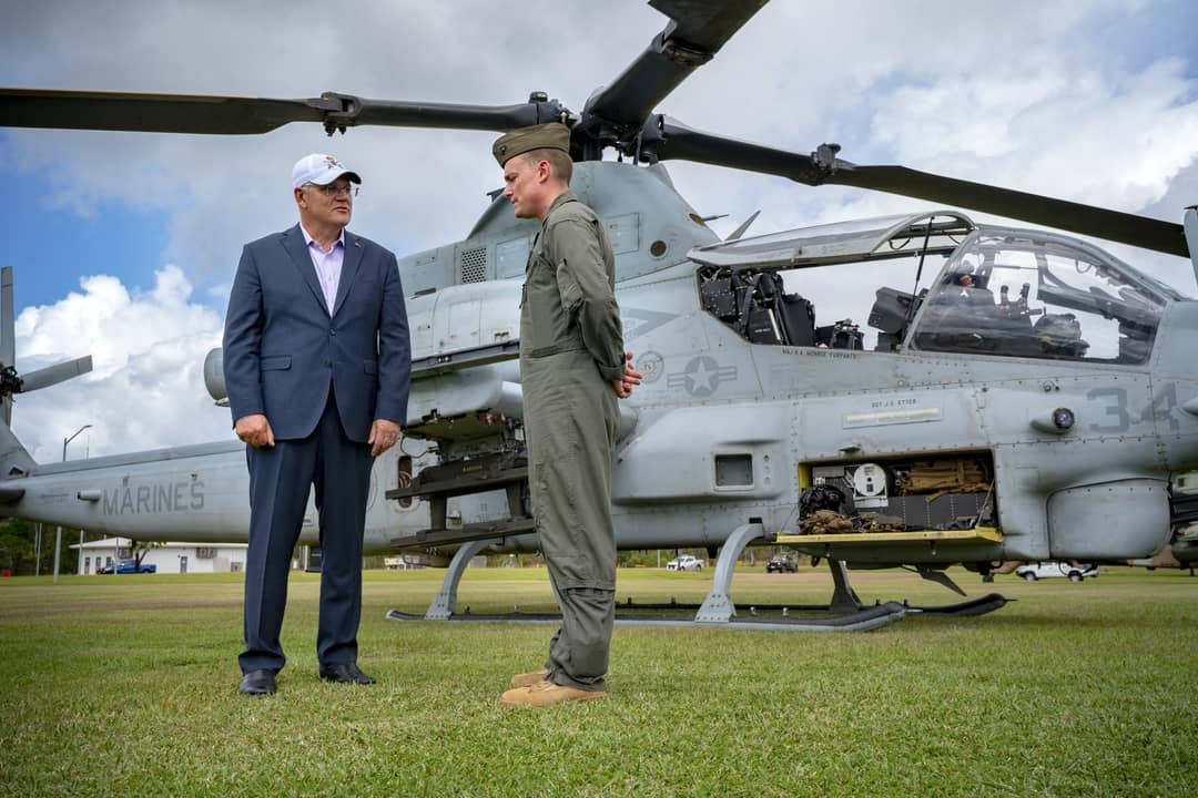 Scott Morrison stands talking with a serviceman in front of a military helicopter.