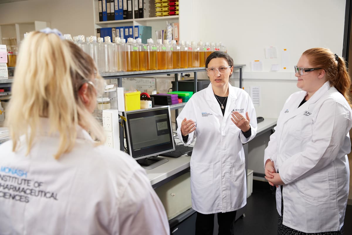 Associate Professor Cornelia Landersdorfer talks to two colleagues in a lab