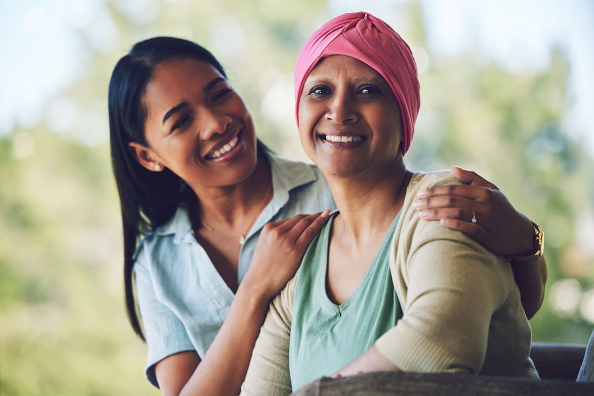 A young woman sits with her mother who is going through cancer treatment.