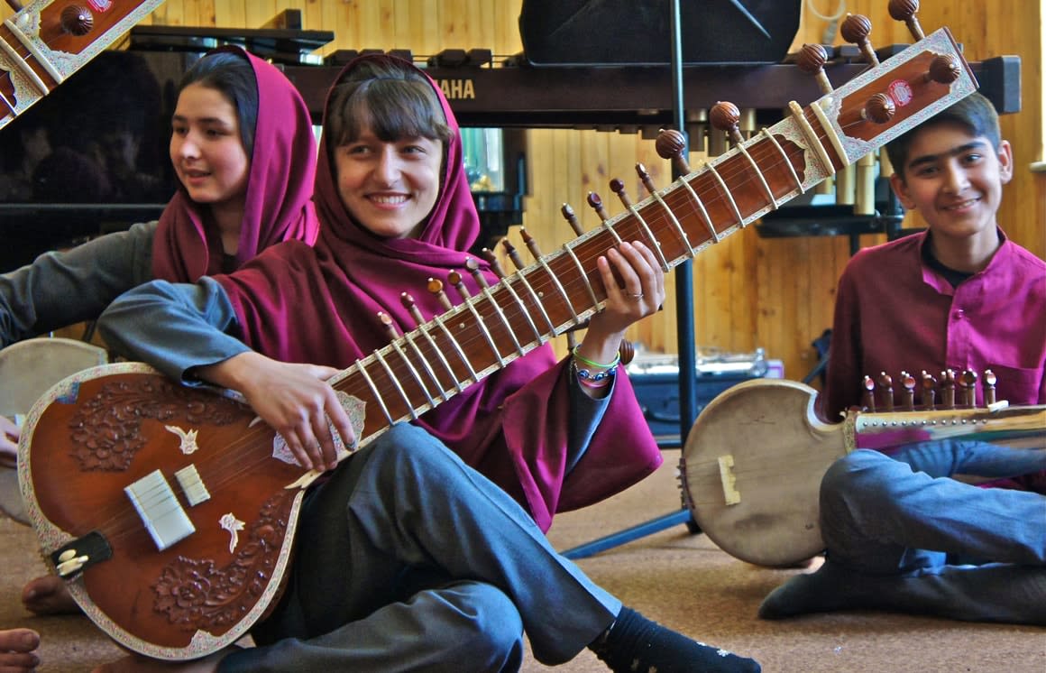Smiling Afghan children sitting, plating traditional instruments