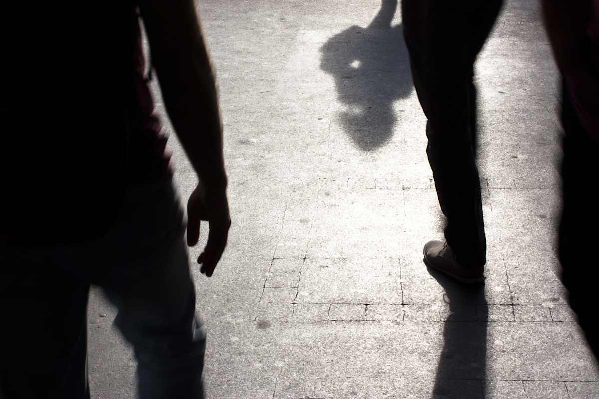 Blurry silhouettes and shadows of people walking on the city sidewalk