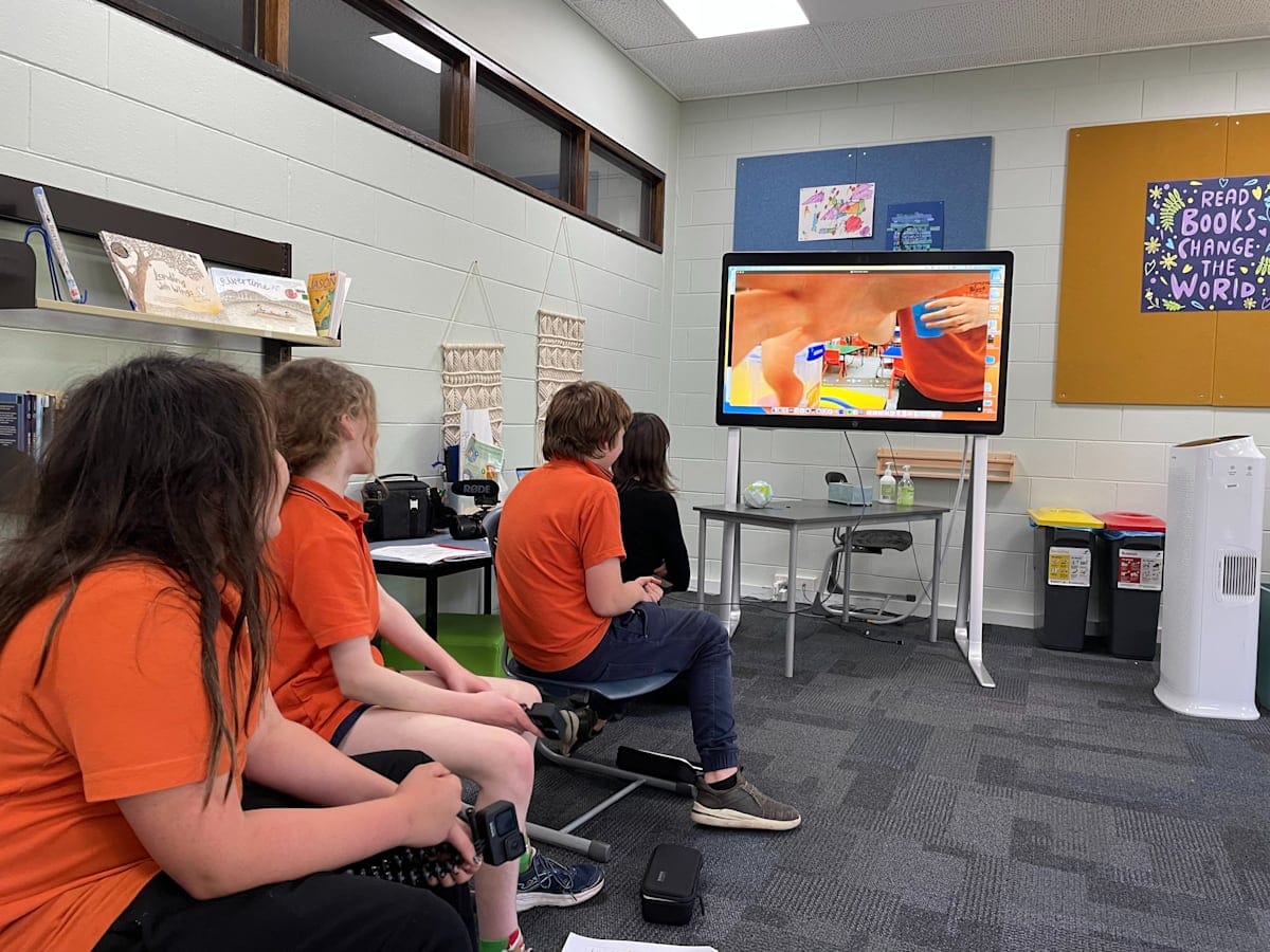 Children in a classroom watching a video on television.