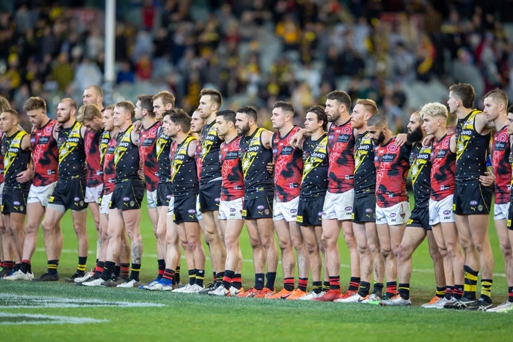 Essendon and Richmond AFL players line up with their arms around each other before the 2019 ‘Dreamtime at the G‘ football match