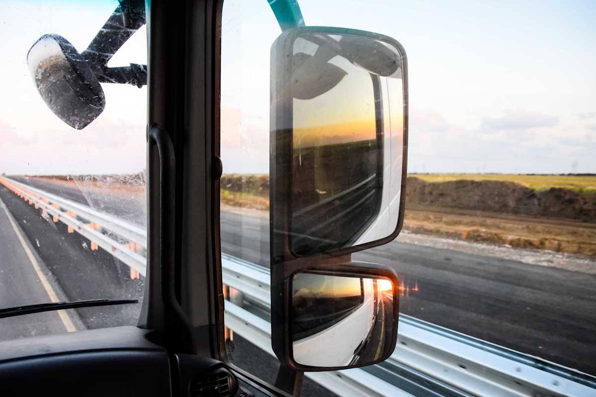 Rear-view mirrors and open road as seen from the cab of a truck