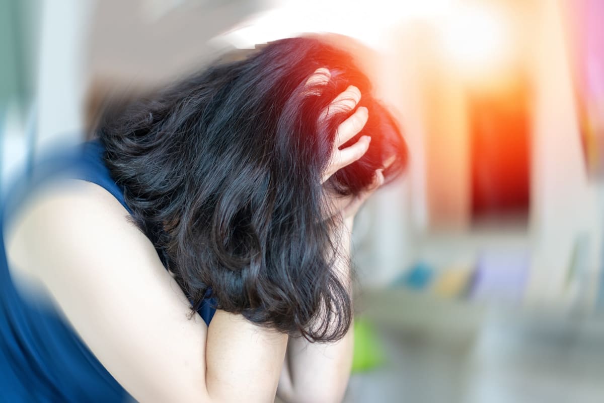 A woman holding her head, face obscured by her hair