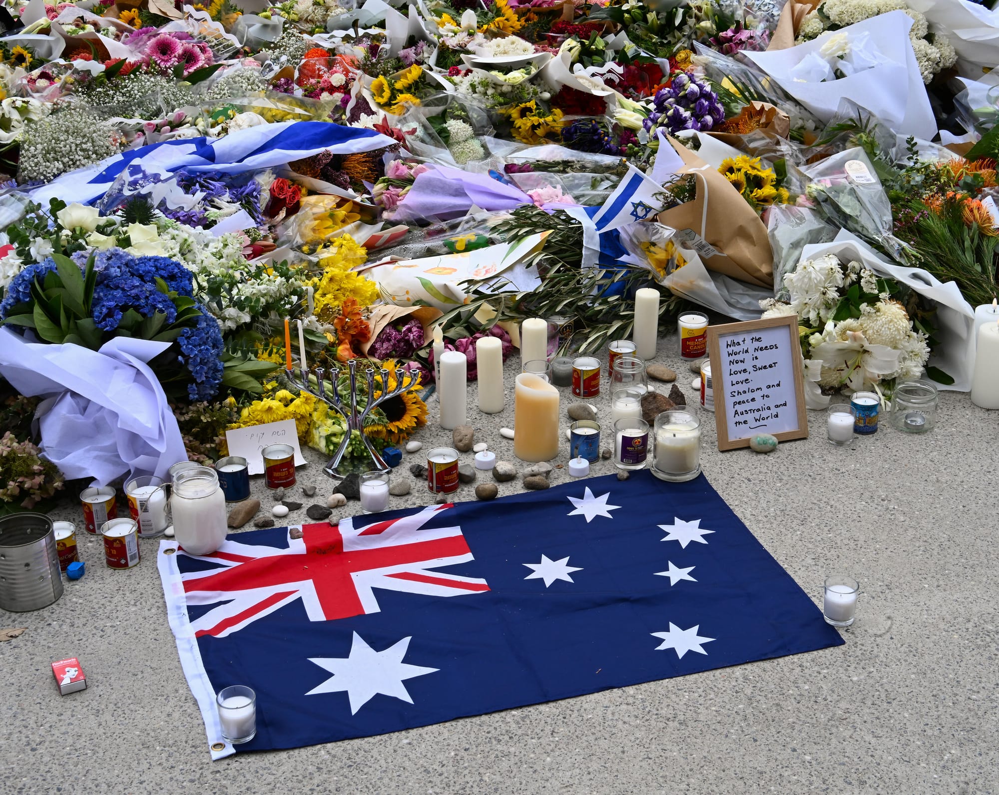 Tributes for the Bondi shooting victims, including Australian and Israeli flags, flowers and candles.