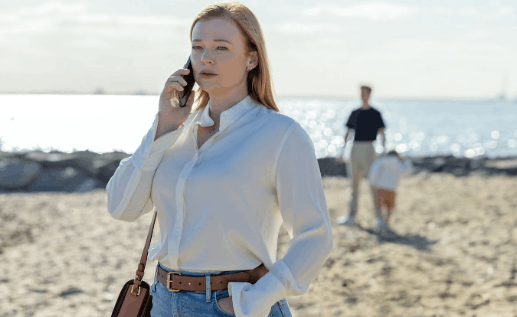 Sarah Snook in a scence All Her Fault, standing on a beach and talking on the phone.
