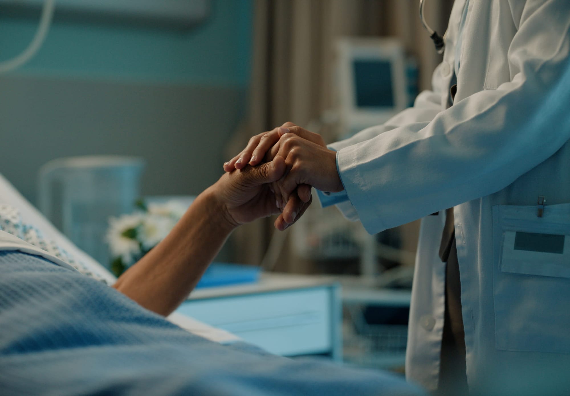 Doctor holding the hand of a patient laying in bed in hospital