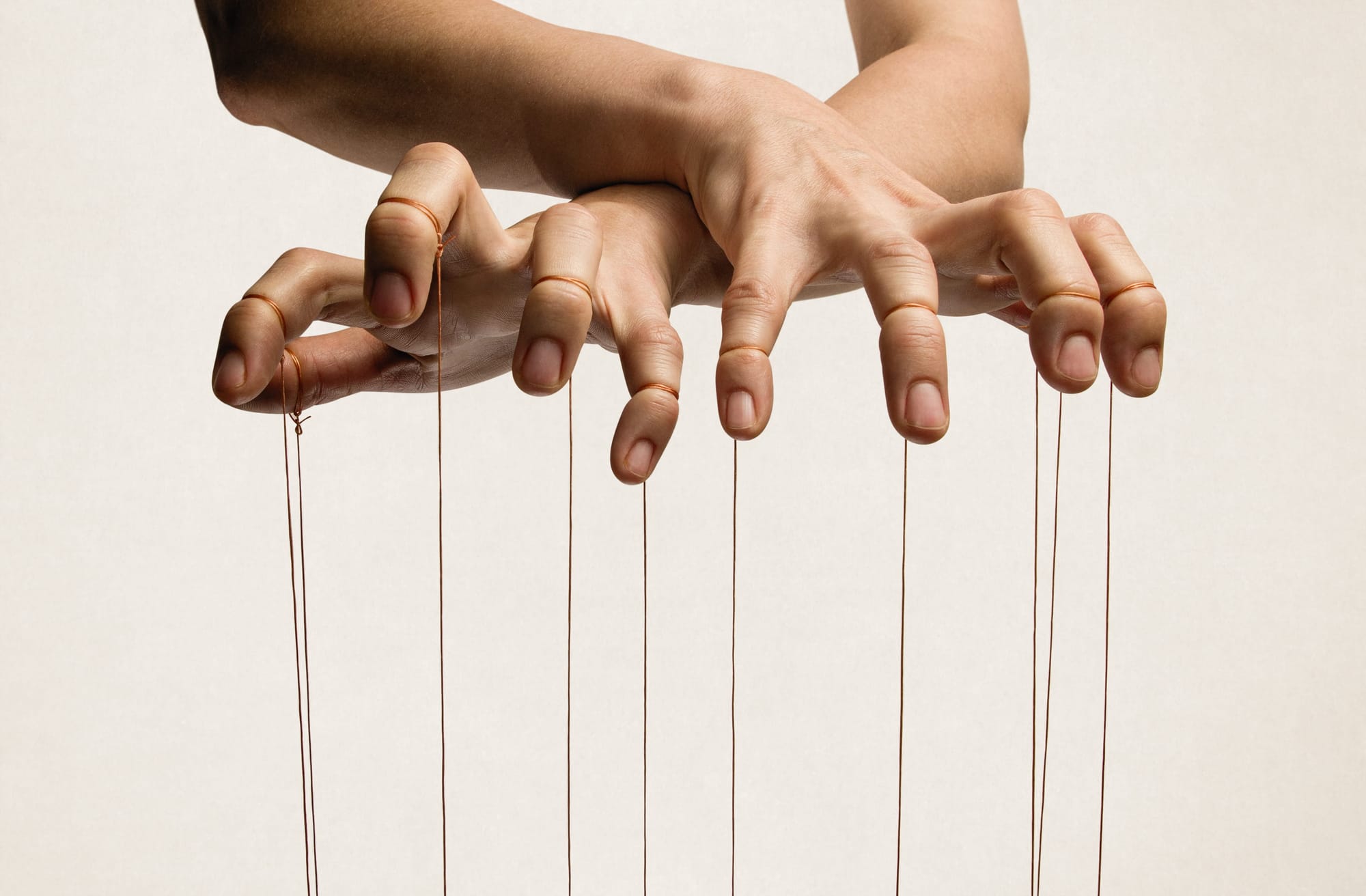 A puppeteer's hands with strings on each finger.