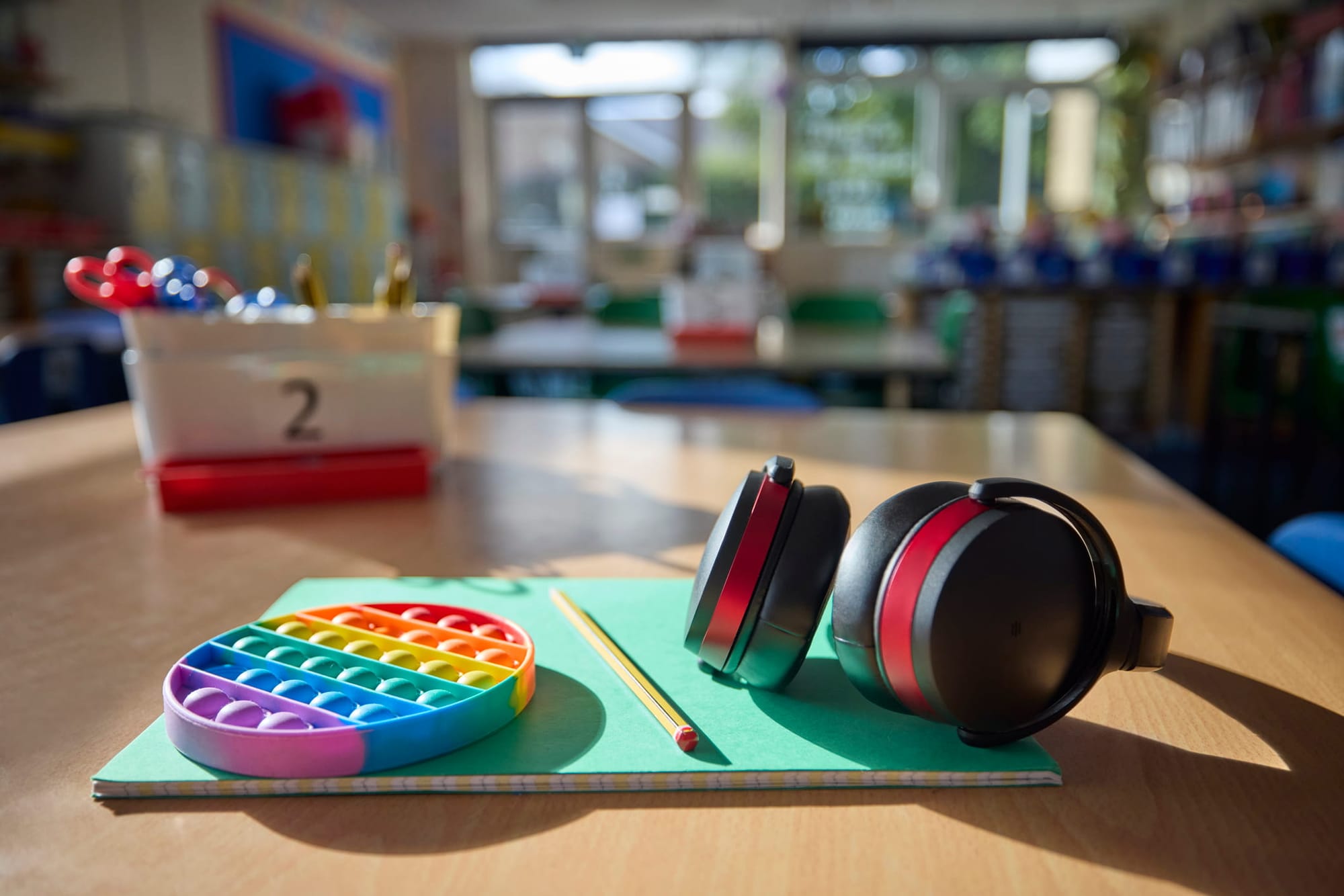Headphones and fidget toy to help child with autism on a table in ampty classroom