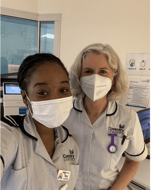 Jenny Gamble and another person in uniform, both wearing masks smiling for a selfie in a hospital setting 