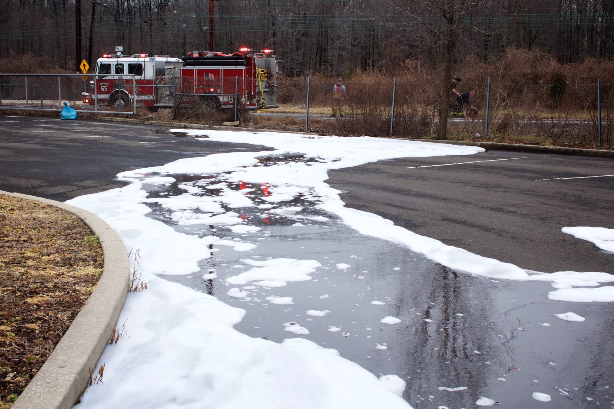A fire engine in the background with firefighting foam across a road in the foreground