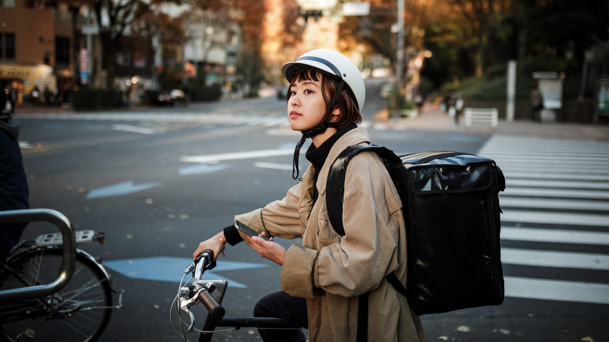 Young woman riding a bike with delivery bag, working for a food delivery app.