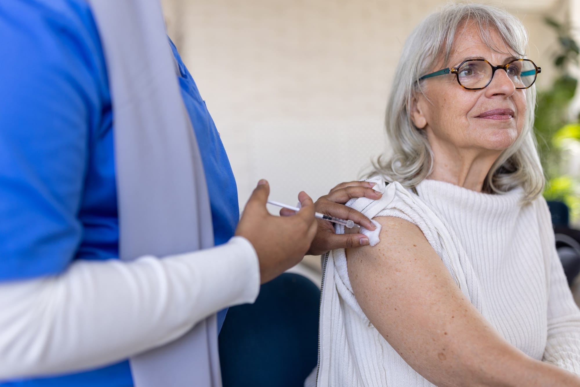 Nurse vaccinating elderly woman.