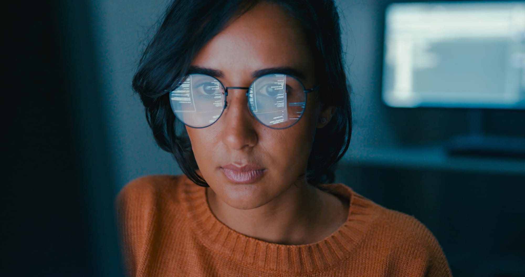 Female computer programmer at work, the screen reflected in her glasses