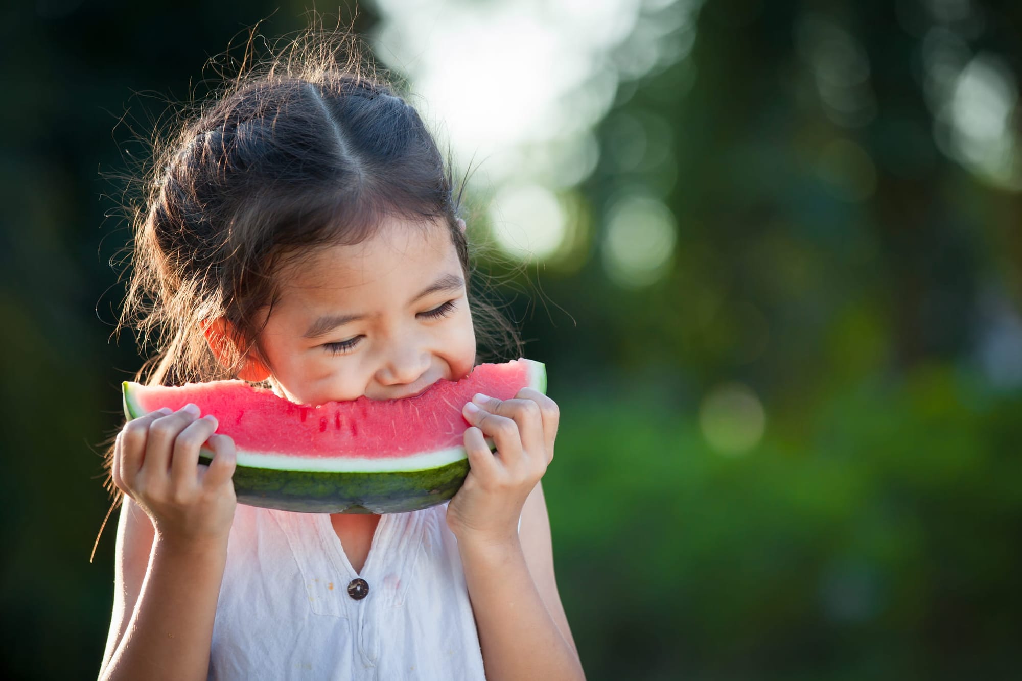 Happy young girl eating watermelon