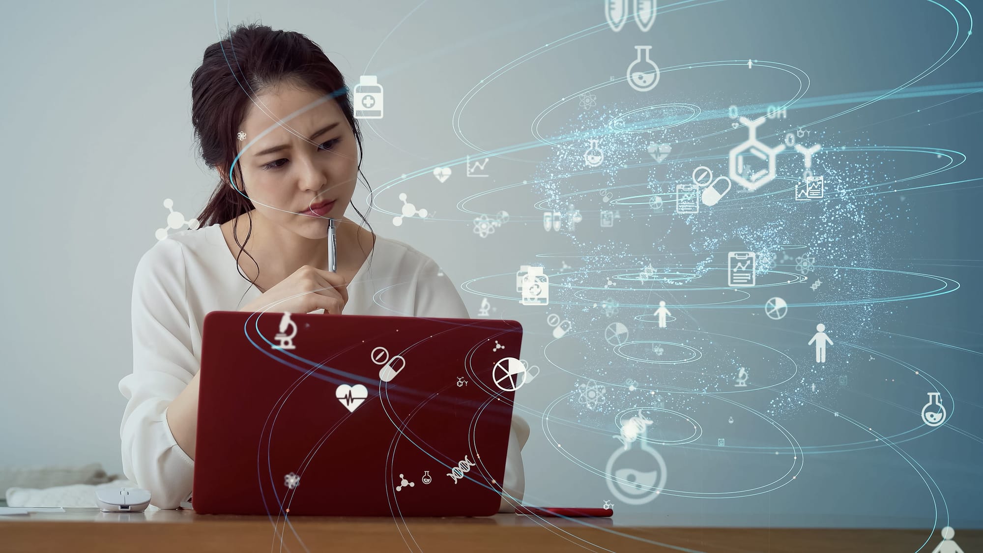 Young Asian woman working with her laptop as medical icons swirl in the foreground 